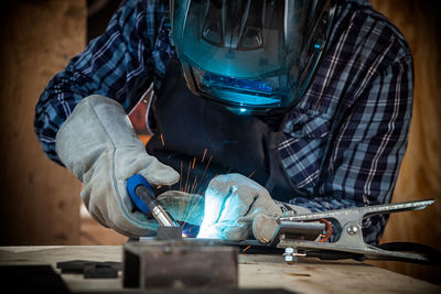 Close up of a young man welder in uniform, welding mask and welders leathers, weld