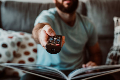 Midsection of man changing tv channel