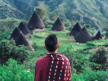 Rear view of man standing against huts on mountain