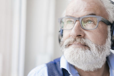 Mature man wearing glasses and headphones at the window