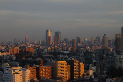 Aerial view of cityscape against cloudy sky