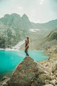 Man standing on rocks by mountain against sky