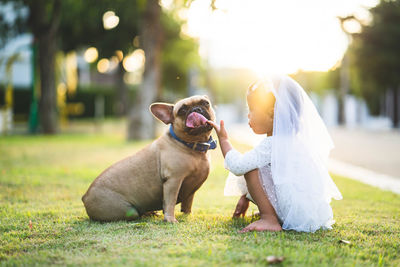 Girl crouching by dog on grass