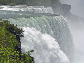 Low angle view of waterfall in forest against sky