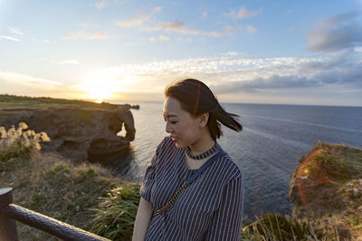 Woman standing by sea against sky