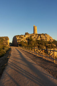 Road leading towards castle against clear blue sky