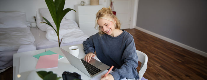 Smiling young woman using digital tablet while sitting on table