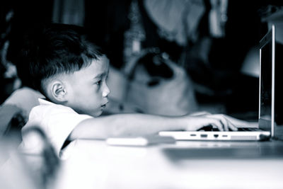 Side view of boy using laptop on table at home