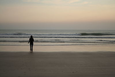 Silhouette man standing on beach against sky during sunset