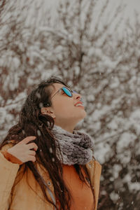 Portrait of smiling young woman standing against plants