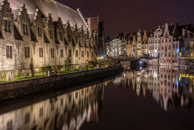 Buildings reflecting on canal in city at night