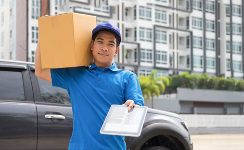 Portrait of male worker delivering package in city