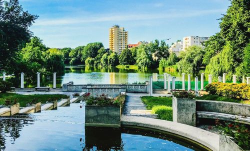 Scenic view of lake by park against buildings in city