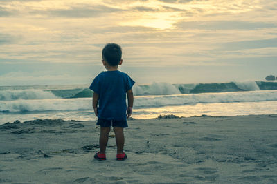 Rear view of boy standing at beach