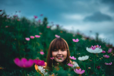 Portrait of smiling woman with pink flowers against blurred background