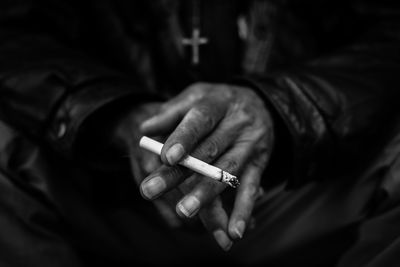 Midsection of man holding cigarette