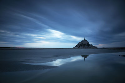 View of building by beach against cloudy sky