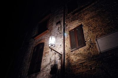 Low angle view of illuminated street light against wall