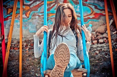 Full length of young woman standing against graffiti