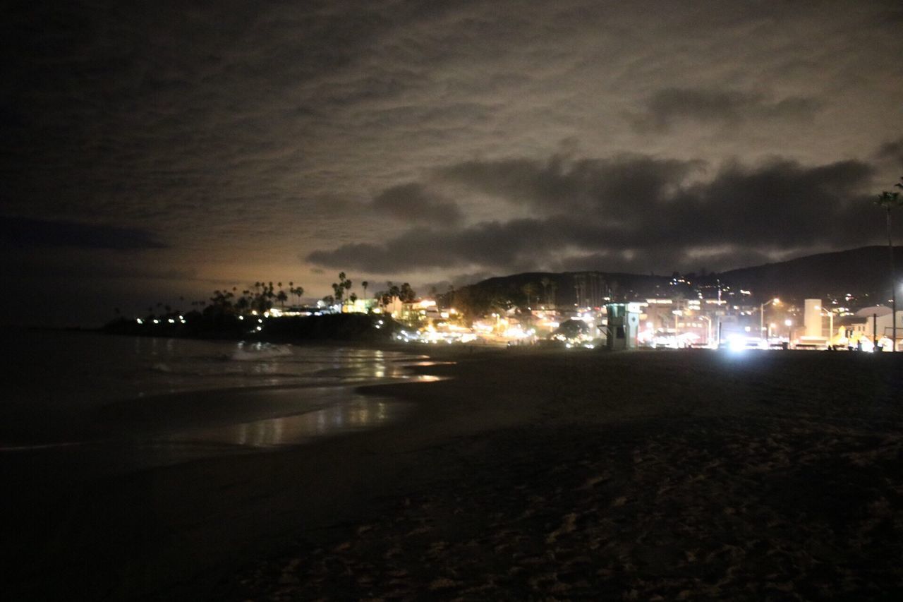 ILLUMINATED CITY BY SEA AGAINST SKY