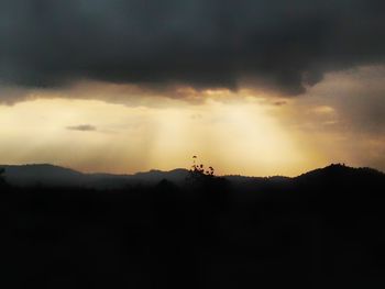 Silhouette person on landscape against sky during sunset