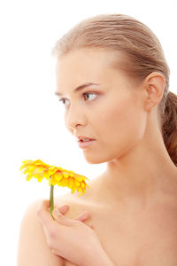 Close-up portrait of young woman holding pink flower against white background