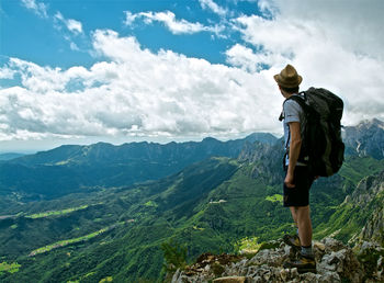 Rear view of man standing on mountain against sky