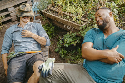 Smiling young male volunteers resting in urban farm