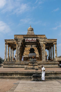 An old man worship lord shiva on thanjavur big temple in low angle view of temple against sky