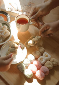 Hands of people with sweet food and tea cup