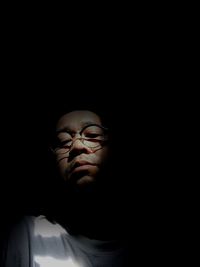 Low angle view of man wearing eyeglasses in darkroom