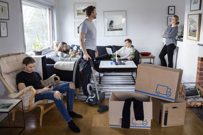 Parents working while siblings sitting in living room at new house