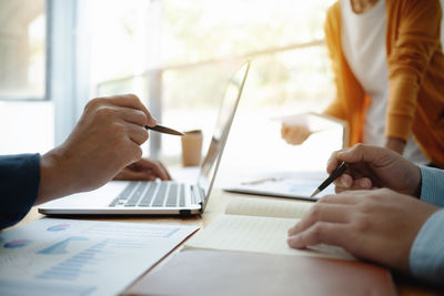 Midsection of woman using mobile phone while sitting on table