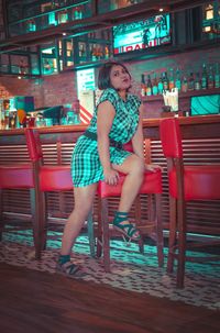Full length portrait of woman sitting on table