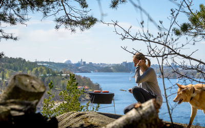 Side view of woman preparing meat on barbecue by river