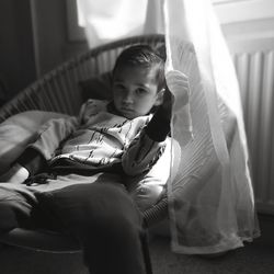 Portrait of cute boy sitting on wicker chair at home 