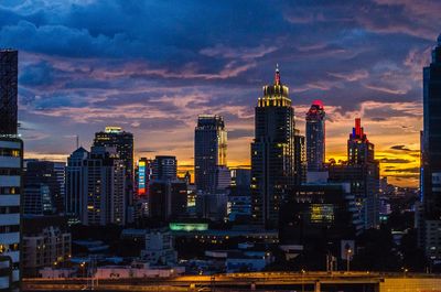 Illuminated buildings in city against sky during sunset