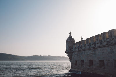 Historical building by sea against clear sky