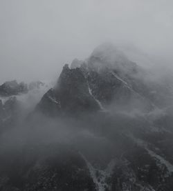 Scenic view of mountains in foggy weather against sky