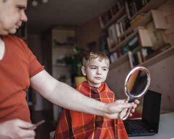 Father and son using smart phone at home