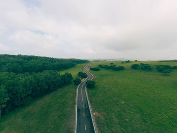 Scenic view of road amidst field against sky