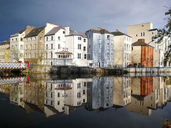 Reflection of buildings in river against sky