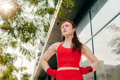 Low angle view of woman looking away while standing against trees