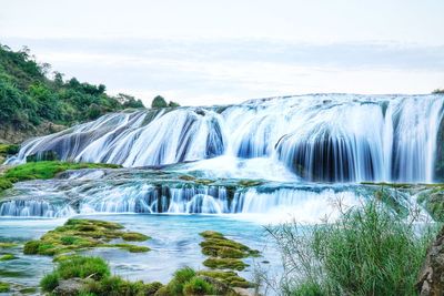 Scenic view of waterfall against sky