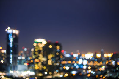 Defocused image of illuminated city against sky at night