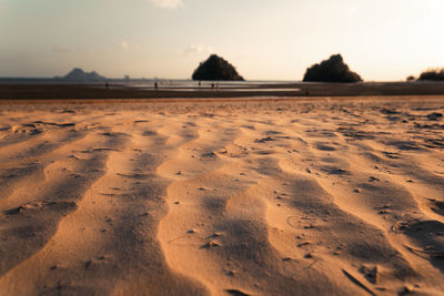 Footprints on sand at beach against sky