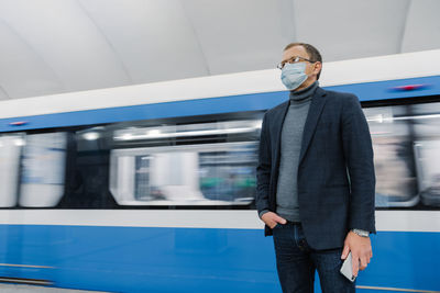 Man standing by train at railroad station