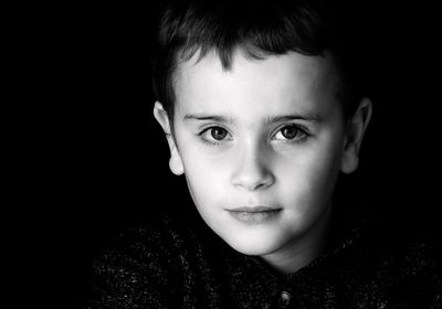 Portrait of boy against black background