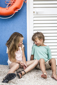 Siblings sitting outside closed door