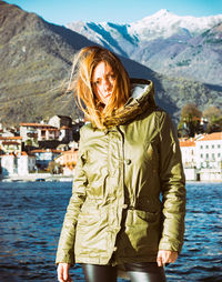 Portrait of smiling young woman standing against river